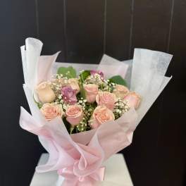 Bouquet of pale pink roses wrapped in pink and white paper