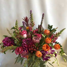 Mixed bouquet of pink, orange, and purple flowers in a glass vase