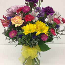 Colorful mixed bouquet in a glass vase with a yellow ribbon