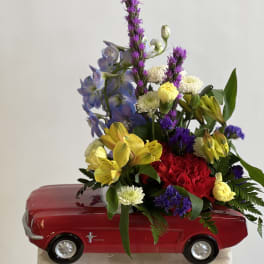 Mixed flower arrangement in a red toy car container