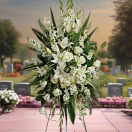 Tall white funeral spray with lilies and greenery on a stand