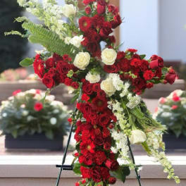 Cross-shaped floral tribute of red and white roses on an easel