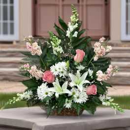 Basket arrangement of pink roses, white lilies, and daisies