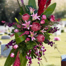 Tall tropical floral spray with pink lilies and red protea on a stand