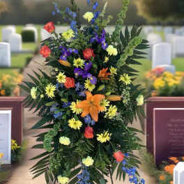 Tall funeral spray with orange, yellow, purple, and blue flowers