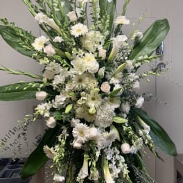 Large white floral standing spray with lilies, roses, and daisies