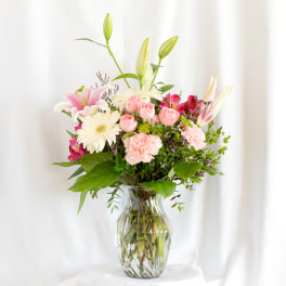 Mixed bouquet of pink and white flowers in a clear glass vase