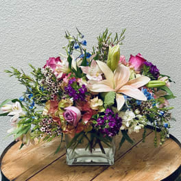 Mixed bouquet in a square glass vase with pink, white, and purple flowers