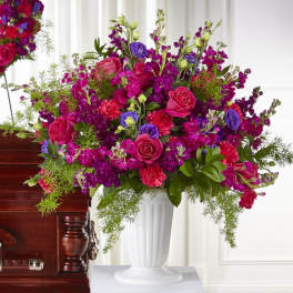 Large pink and purple floral arrangement in a white vase