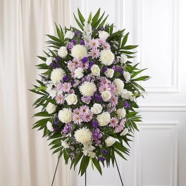 Standing floral spray with white, pink, and purple flowers on a tripod easel