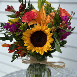 Mixed bouquet with a sunflower and orange lily in a glass vase