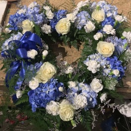 Blue and white floral wreath with cream roses and a blue ribbon