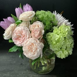 Mixed bouquet of pale pink roses, green hydrangea, and white daisies in a glass vase