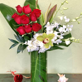 Red roses and white orchids arranged in a tall glass vase