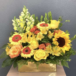 Yellow and orange mixed flower arrangement in a gold rectangular vase