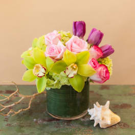 Pink roses and green orchids arranged in a dark vase