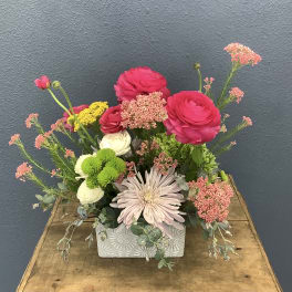 Mixed bouquet in a patterned rectangular vase with pink, white, and green blooms