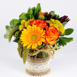 Bouquet of orange roses and a yellow gerbera daisy in a wrapped vase