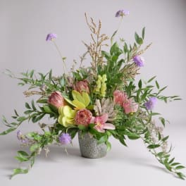 Mixed floral arrangement in a textured vase with pink, purple, and green blooms