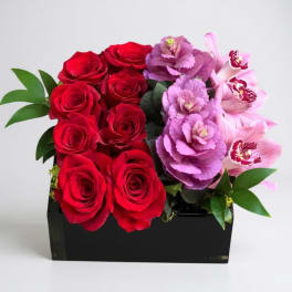 Red roses and pink orchids arranged in a black box