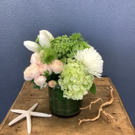White and pale pink flowers arranged in a green vase with starfish accents
