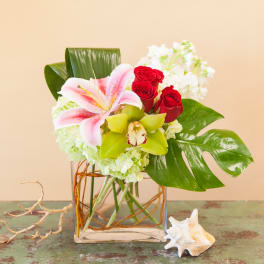 Bouquet of pink lilies, red roses, and white flowers in a glass vase