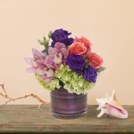 Bouquet of purple, pink, and coral flowers in a striped glass vase