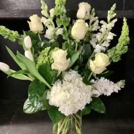 White roses and snapdragons arranged in a clear glass vase