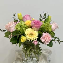 Mixed pink and yellow flowers arranged in a glass vase