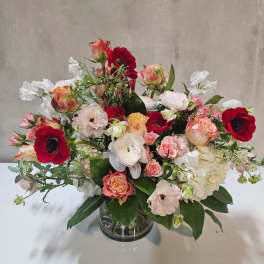Mixed bouquet of red, pink, and white flowers in a glass vase