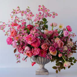 Pink floral arrangement in a stone urn vase