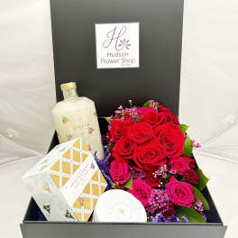 Boxed gift set with red roses, a bottle, and packaged bath items