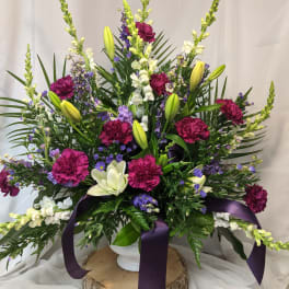Large floral arrangement with purple and white flowers in a white vase