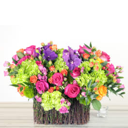 Colorful bouquet of roses, hydrangeas, and orchids in a twig basket