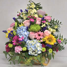 Colorful mixed flower arrangement in a basket with roses, hydrangeas, and daisies