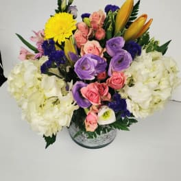 Mixed bouquet in a round vase with pink, purple, yellow, and white flowers
