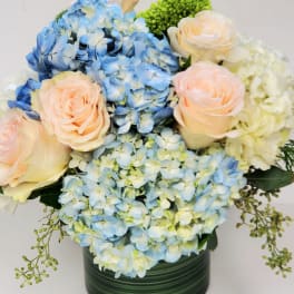 Blue hydrangeas and pale roses arranged in a green vase