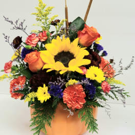 Pumpkin-shaped vase with sunflowers, roses, and carnations