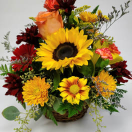 Mixed bouquet with a sunflower, roses, and chrysanthemums in a wicker basket