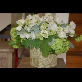 White floral arrangement in a textured vase with green blooms