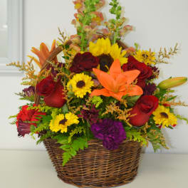 Basket arrangement with red roses, yellow daisies, and an orange lily