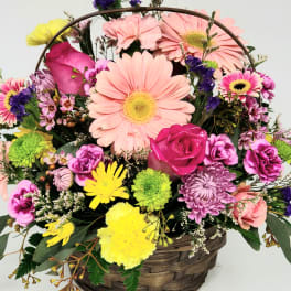 Mixed bouquet in a woven basket with pink daisies and roses