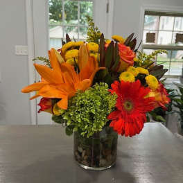 Bright mixed bouquet in a glass vase with orange lilies and red gerbera daisies