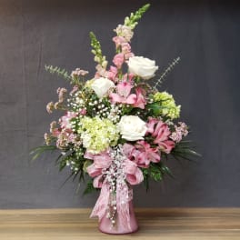 Pink and white floral arrangement in a pink vase with lace ribbon