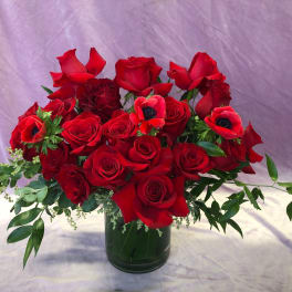 Red roses and anemones arranged in a glass vase