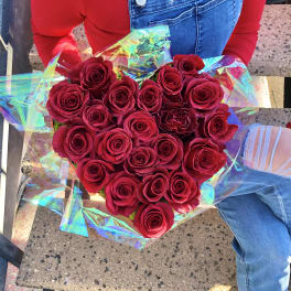 Heart-shaped bouquet of red roses wrapped in iridescent paper