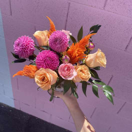 Handheld bouquet of pink and peach flowers with orange accents