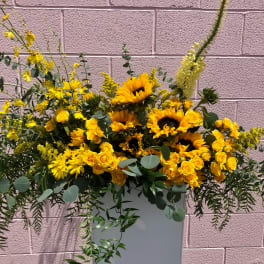 Yellow sunflowers and roses arranged in a tall white vase