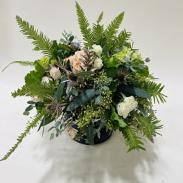 Low floral arrangement with white and peach roses in a dark container