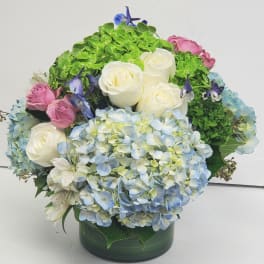 Bouquet of white roses, blue hydrangeas, and pink roses in a green vase